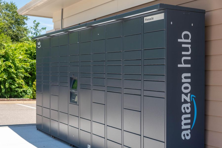 Pinnacle Apartments Amazon Hub locker station outdoors against a building, with trees in the background.