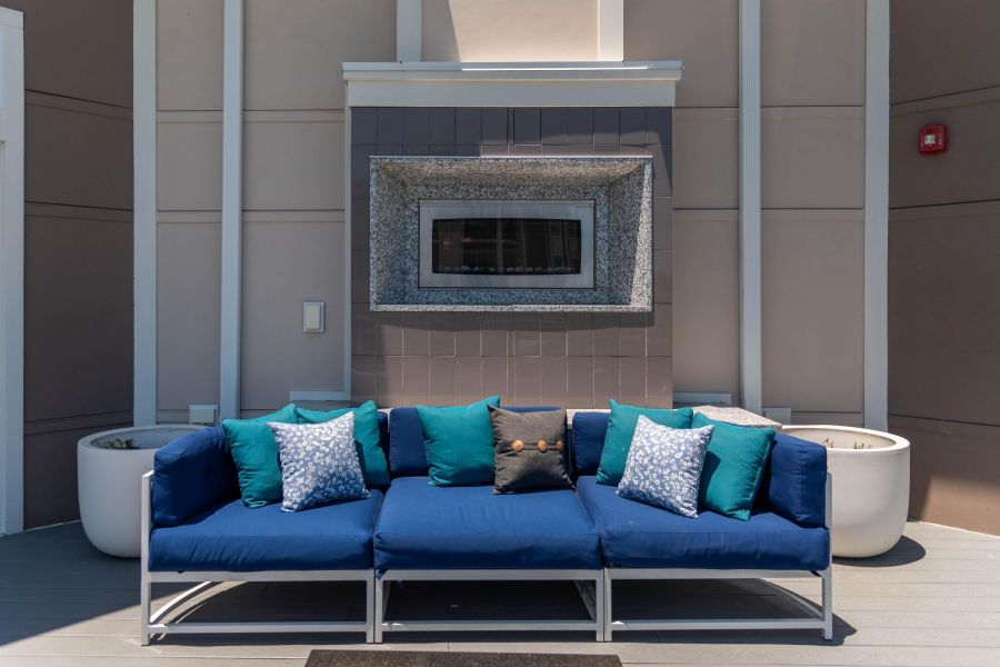 Pinnacle Apartments Modern outdoor seating area with blue cushions, patterned pillows, and a decorative wall feature behind.